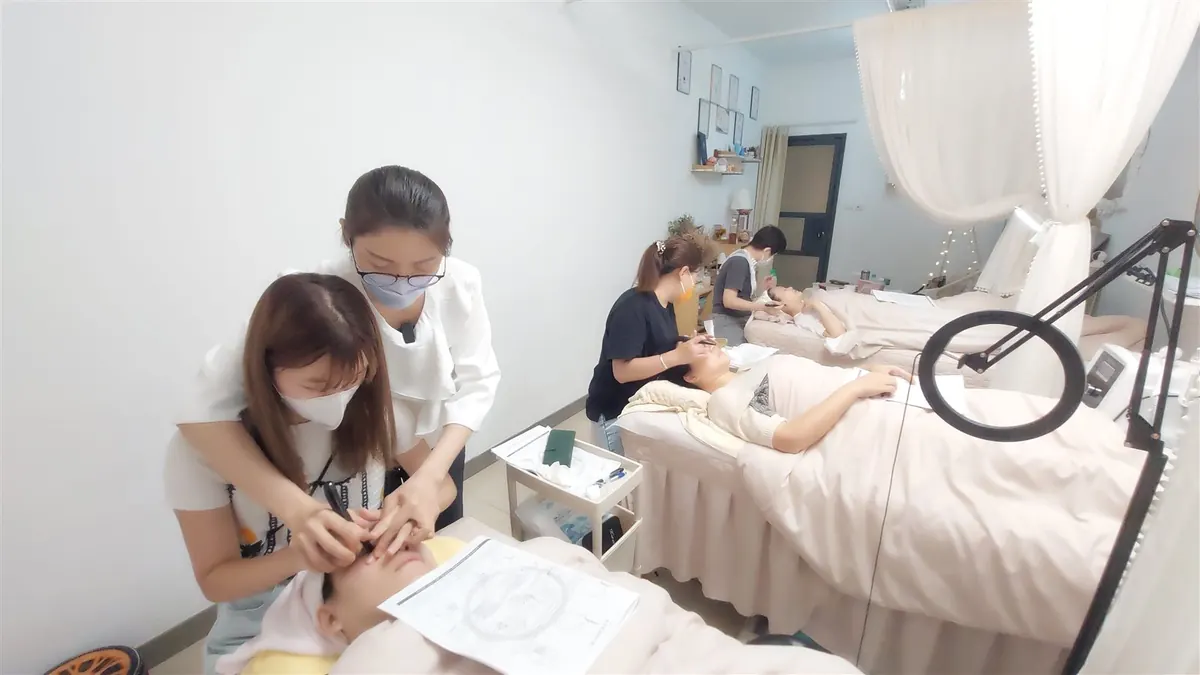 Hands guiding a slow, gentle upward pass along the cheek during a hands-on bojin lesson.