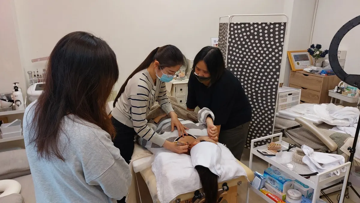 Women practicing gentle bojin strokes on their own faces during a small hands-on class.