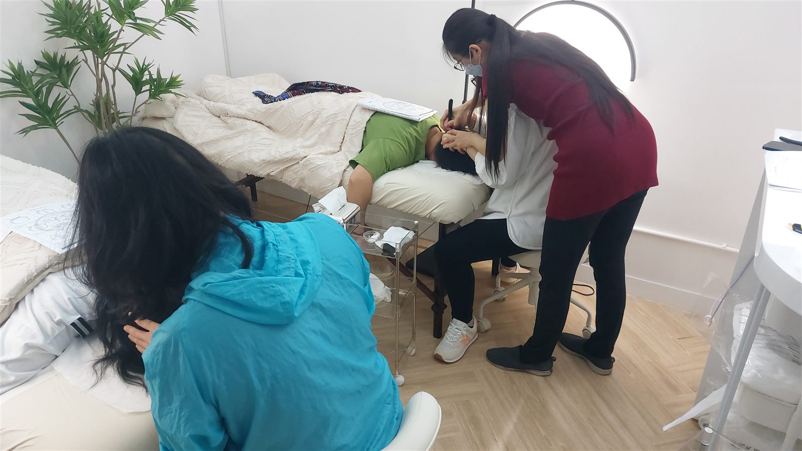 A woman in her fifties resting a smooth stainless steel bojin stick against her forehead in soft daylight